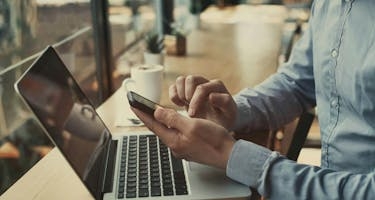 Closeup of hands holding smartphone in cafe