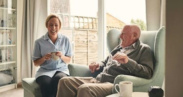 Senior living resident has coffee with caregiver